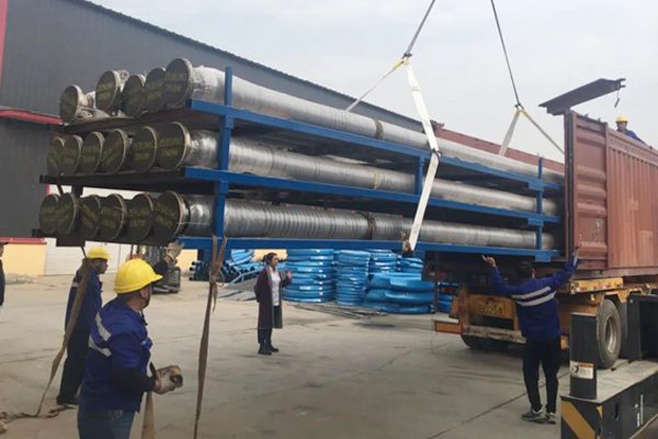 Dock oil hoses being loaded onto a truck with workers wearing helmets, illustrating marine hose transportation.