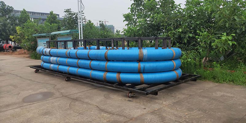 Stack of blue dock oil hoses arranged for shipping or storage, used in marine oil transfer applications