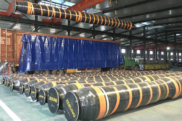 Floating hose and submarine oil hose in Tanzania — stacks of black hoses with yellow stripes at a warehouse.